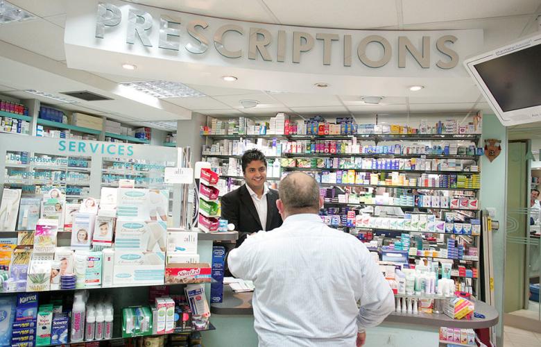 Image of Pharmacy. A Pharmacist helps a patient at the counter. 