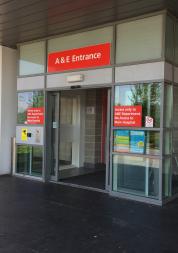 The entrance to A&E at Whiston Hospital.  Red A&E entrance sign above glass sliding doors 