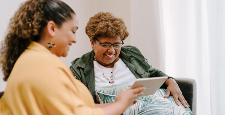 two women socialising looking at an iPad