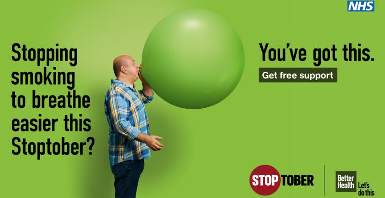 Man blowing up a giant green balloon
