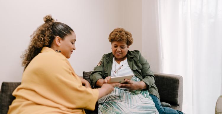two people sitting on a sofa looking at an iPad