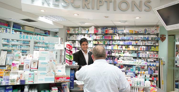Pharmacy counter with staff and customer. 