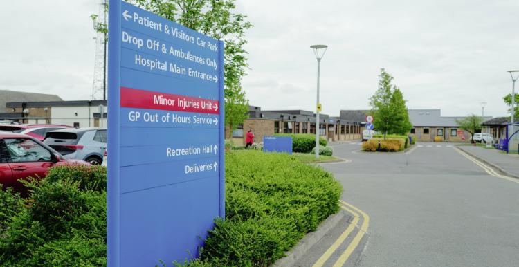Hospital sign, road and car park. 