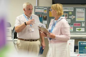 Two people have discussion in front of an information board. 