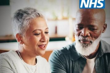 'NHS' Two people look a tablet device together. 