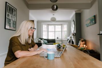 A women reads information on her laptop. 