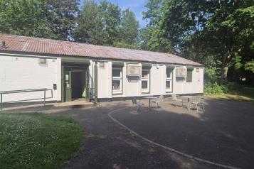 Tea tree café building, surrounded by trees with tables and chairs outside. 