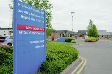 Hospital sign, road and car park. 