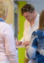 Man completing a form at an engagment event. Two people standing with their backs to the camera